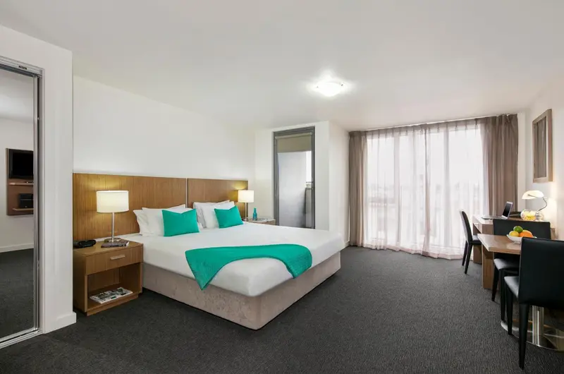 Chambre lumineuse avec un grand lit et un espace repas.