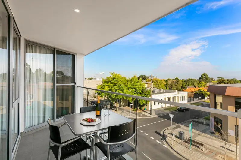 Une table et des chaises sont disposées sur un balcon avec vue sur la ville.