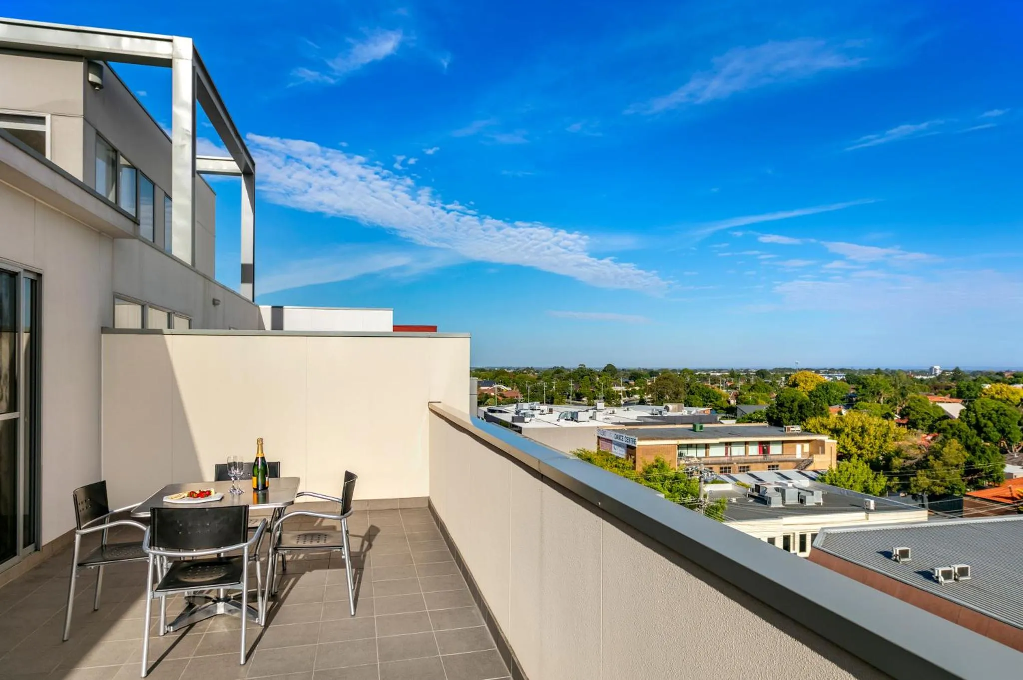 Une table et des chaises sont disposées sur une terrasse avec vue sur la ville.