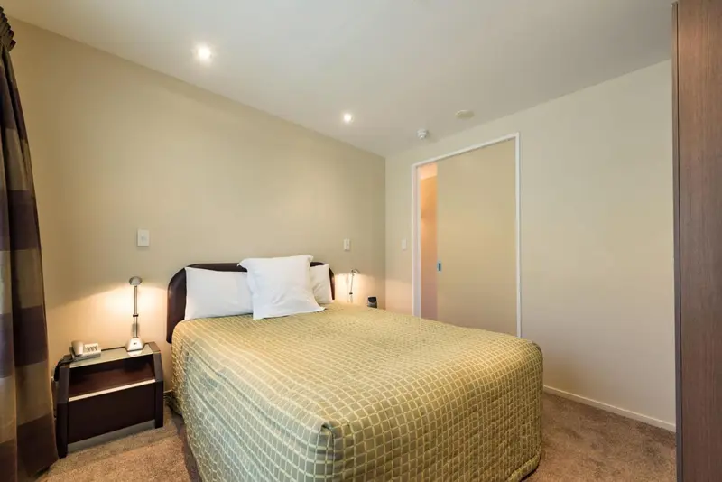 Une chambre lumineuse avec un lit double et des tables de chevet.