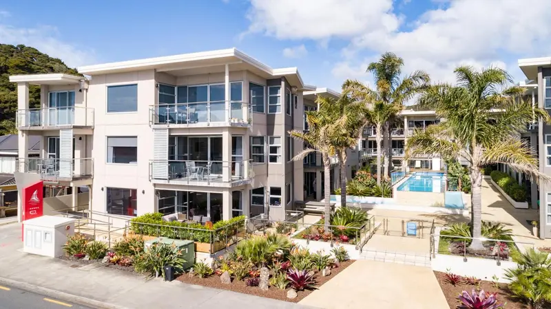Bâtiment moderne avec des balcons et une piscine en contrebas.