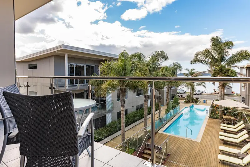 Vue d'une terrasse avec mobilier d'extérieur donnant sur une piscine et des bâtiments.