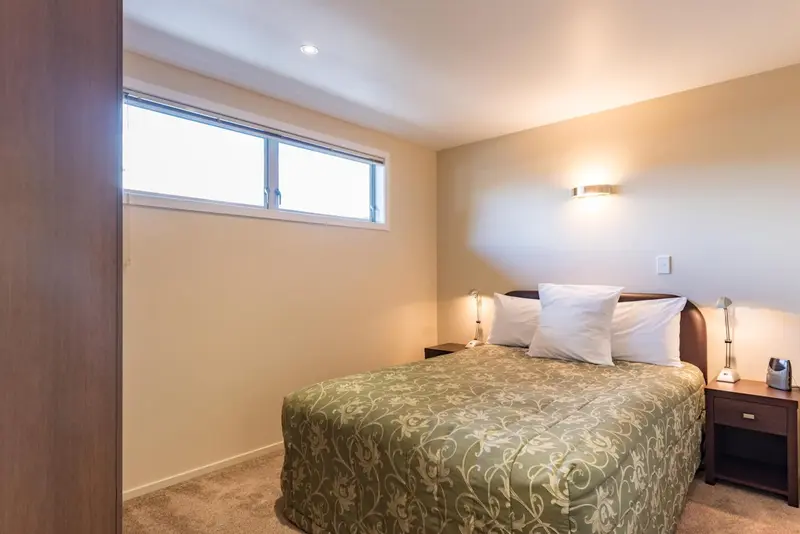 Une chambre lumineuse avec un lit double et une fenêtre.
