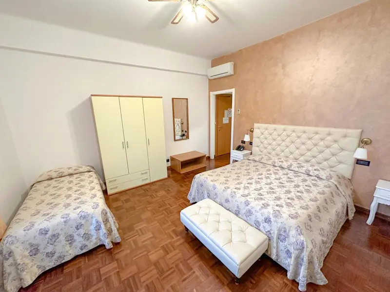 Une chambre lumineuse avec un grand lit et un lit d'appoint.