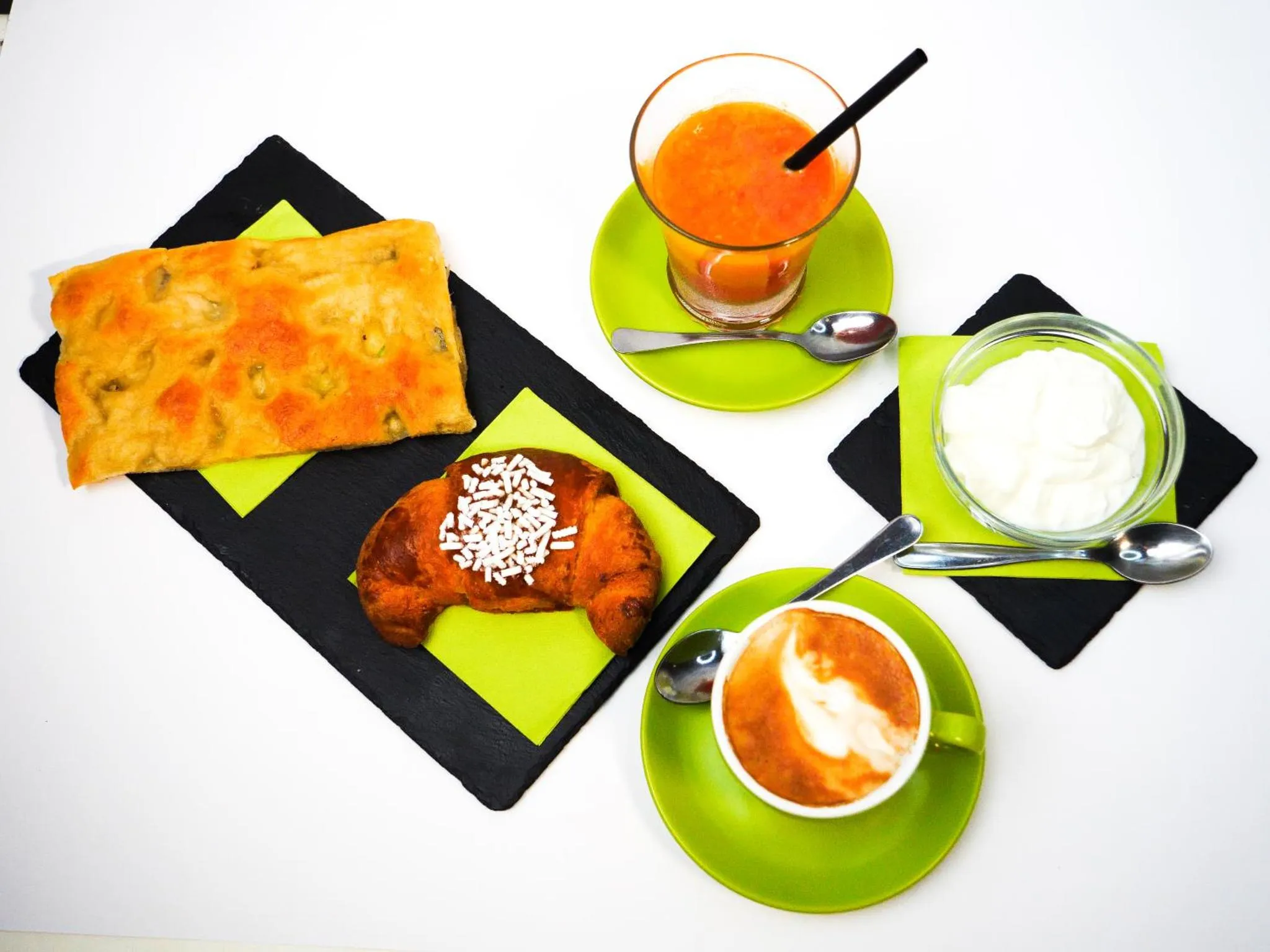 Assortiment de viennoiseries et de boissons sur des sets de table colorés.