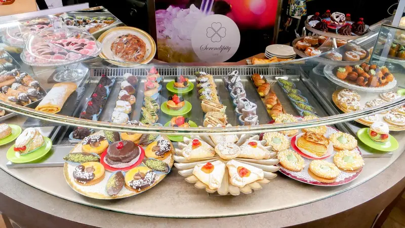 Présentation de pâtisseries variées dans une vitrine réfrigérée.