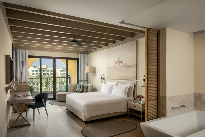 Une chambre lumineuse avec un grand lit et un accès à un balcon.