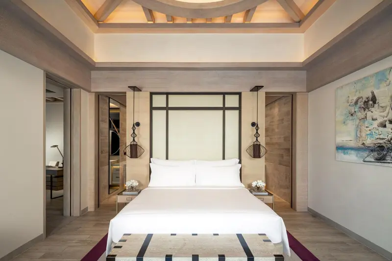 Une chambre lumineuse avec un grand lit recouvert de linge blanc.