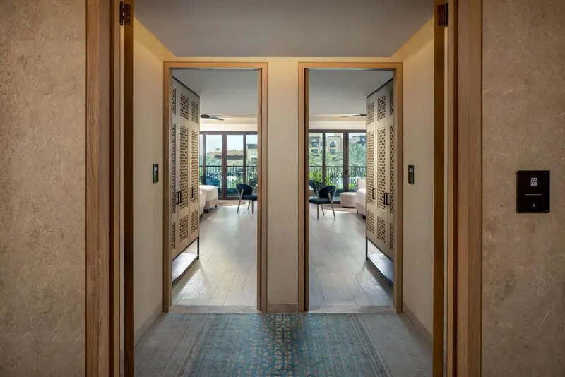 Entrée d'un logement avec deux portes ouvertes sur des pièces lumineuses.