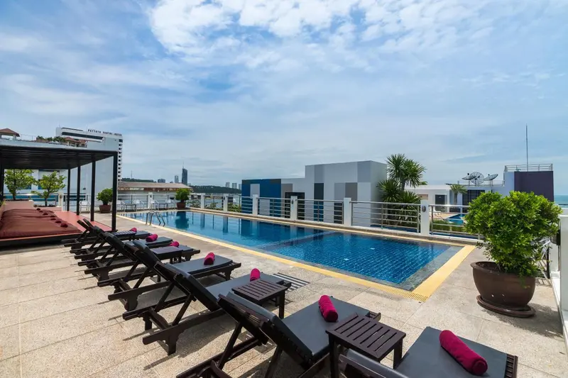 Transats alignés au bord d'une piscine sur un toit-terrasse avec vue sur la ville.