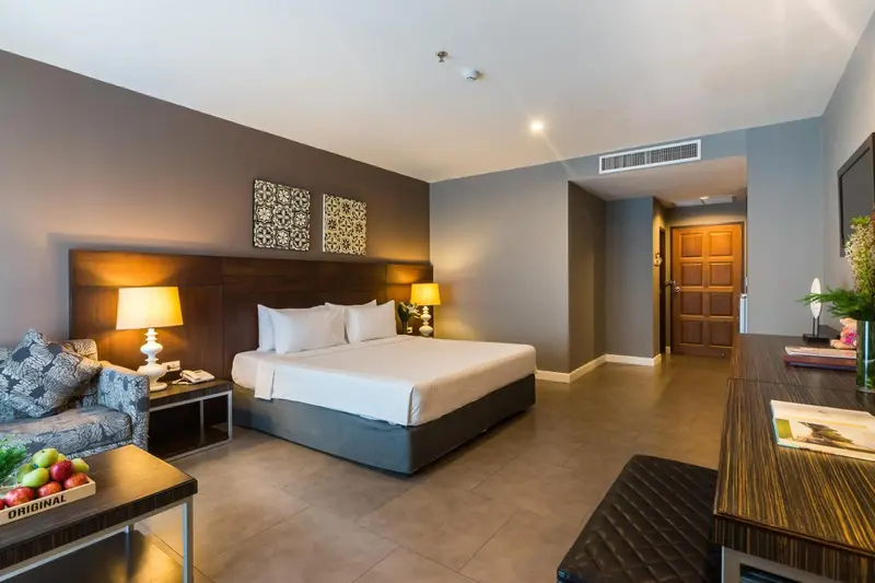 Une chambre lumineuse avec un grand lit et un coin salon.