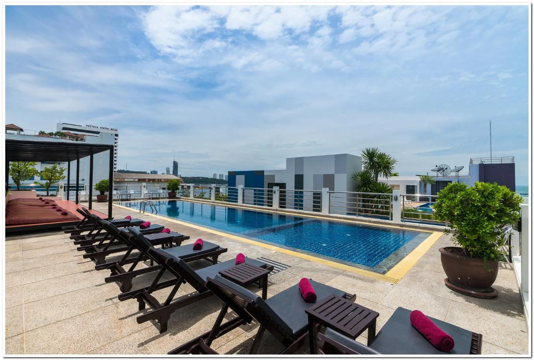 Transats roses alignés au bord d'une piscine sur un toit-terrasse.