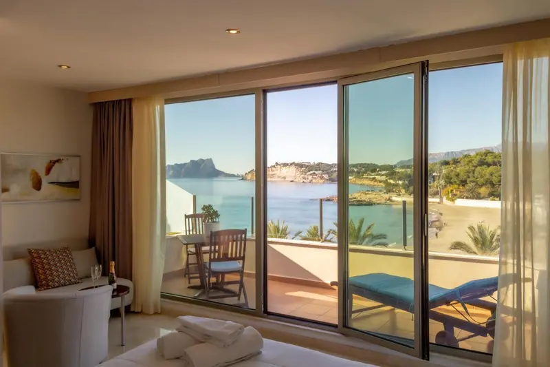 Une pièce lumineuse donne sur une vue mer à travers de grandes baies vitrées.