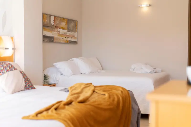 Une chambre lumineuse avec deux lits simples et une décoration murale.