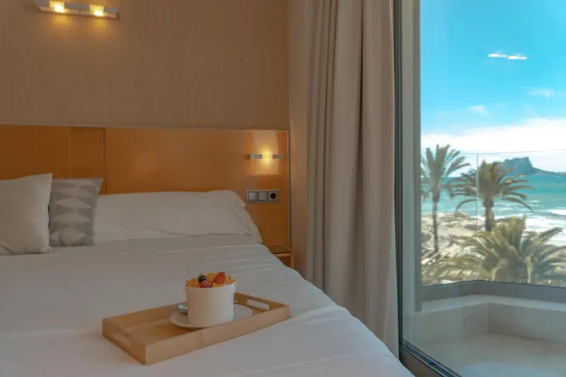 Une chambre lumineuse avec un lit préparé et une vue sur la mer.