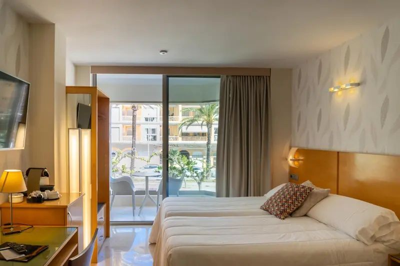 Une chambre lumineuse avec un lit et un accès à une terrasse.