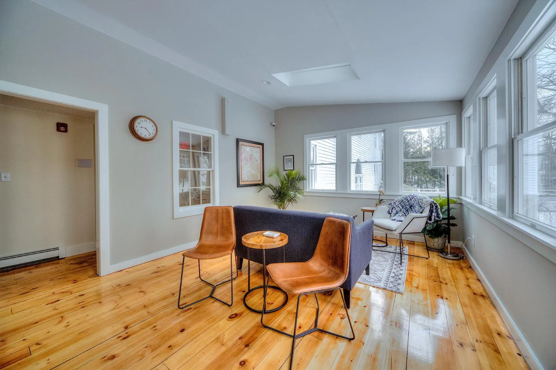 Espace de détente lumineux avec canapés et fauteuils près de grandes fenêtres.