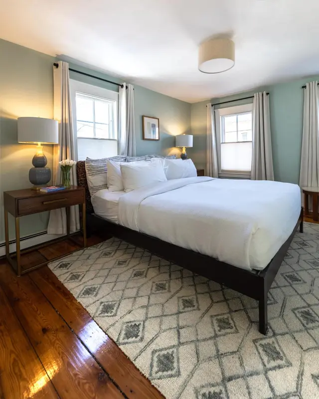 Une chambre lumineuse avec un grand lit recouvert d'une courtepointe blanche.