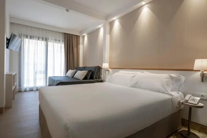 Une chambre lumineuse avec un grand lit et des rideaux clairs.