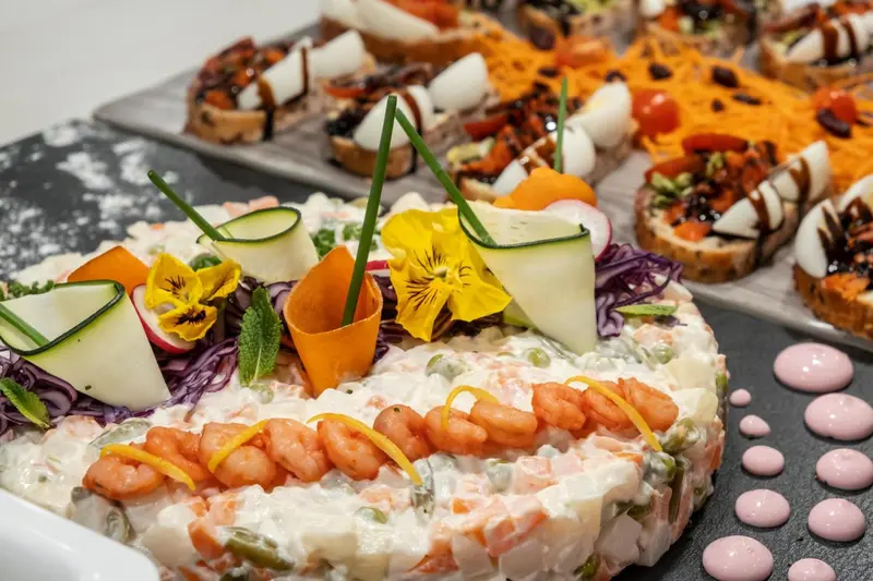 Assortiment de canapés décorés de légumes et de crevettes, présentés sur un plateau.