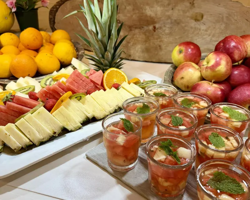 Une table garnie de fruits frais coupés et de verrines colorées.