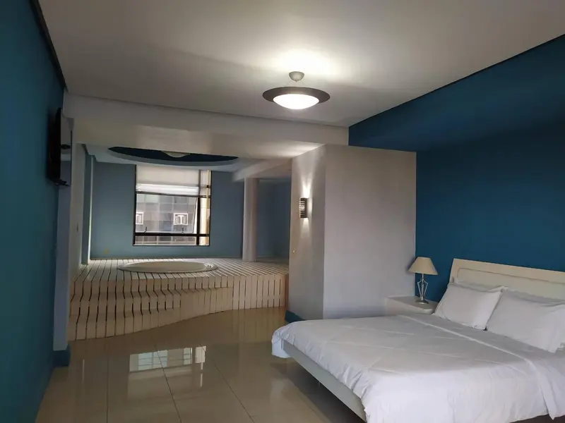 Une chambre lumineuse avec un grand lit et un jacuzzi.