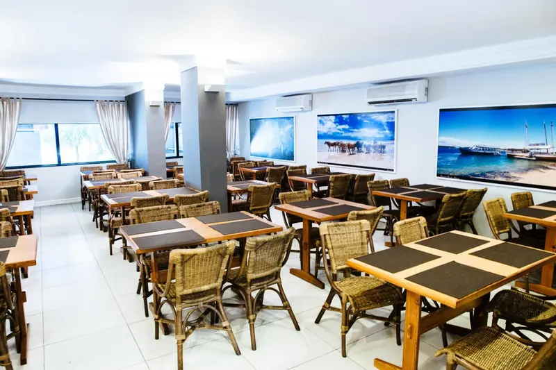 Une salle lumineuse avec des tables et des chaises en osier.