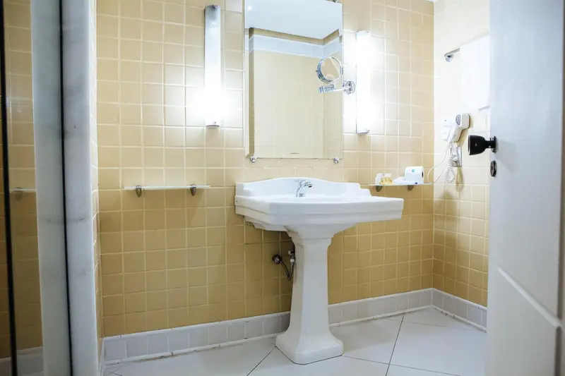 Une salle de bain lumineuse avec un lavabo et un grand miroir.