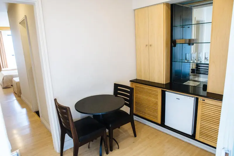 Une petite table ronde avec deux chaises se trouve devant un meuble de rangement avec un réfrigérateur intégré.