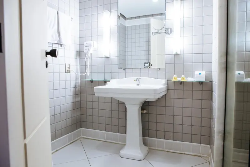 Une salle de bain claire avec carrelage mural et un lavabo sur pied.