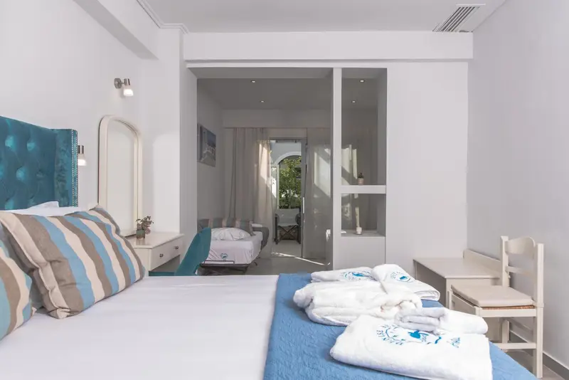 Une chambre lumineuse avec un grand lit et un espace séjour attenant.