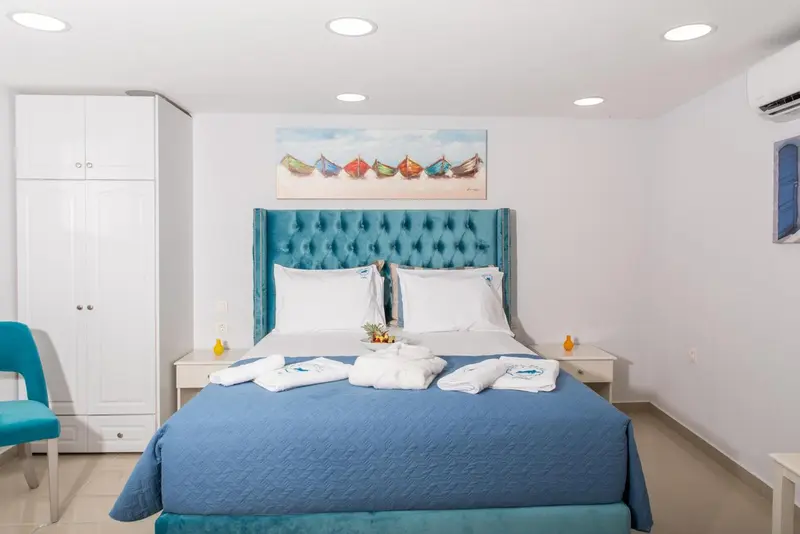 Une chambre lumineuse avec un grand lit recouvert d'une courtepointe bleue et turquoise.