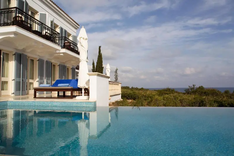 Piscine à débordement avec vue sur la mer et végétation luxuriante.