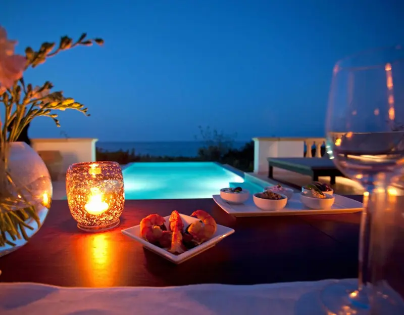 Une table lumineuse avec des amuse-gueules près d'une piscine éclairée.