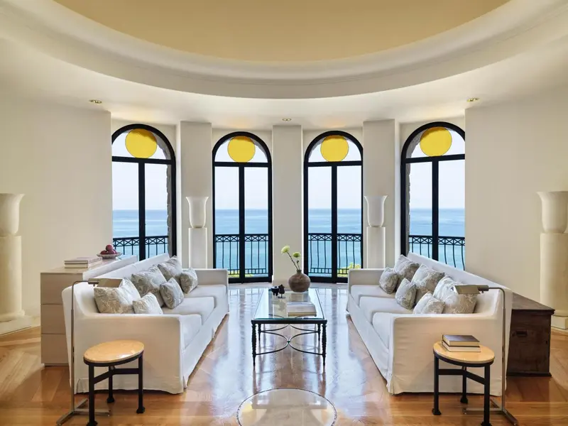 Un salon lumineux avec de larges fenêtres donnant sur la mer.