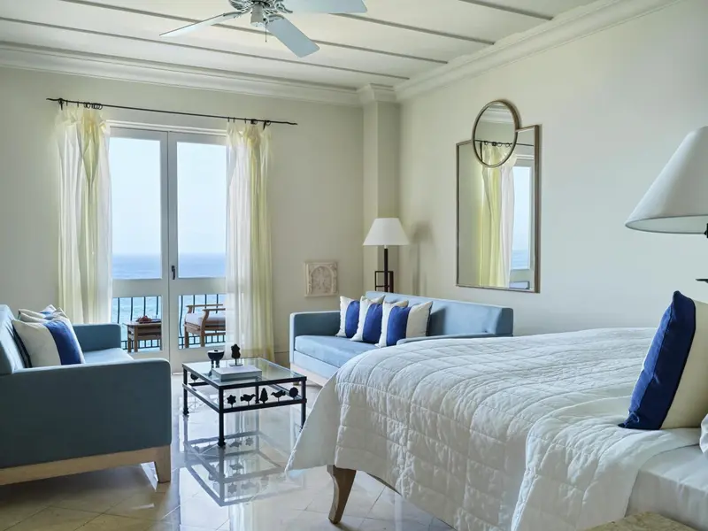 Une chambre lumineuse avec canapé et lit donnant sur la mer.