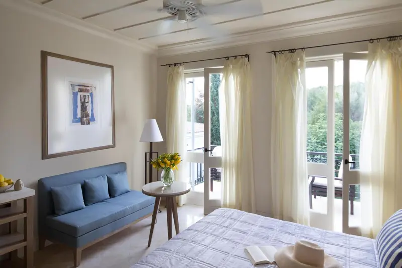 Une chambre lumineuse avec un canapé bleu et un accès à un balcon.