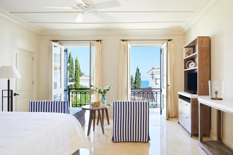 Une chambre lumineuse s'ouvre sur une vue mer par de grandes portes-fenêtres.