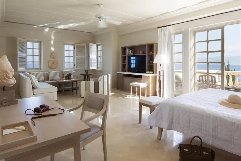 Une pièce lumineuse avec un canapé, une table basse et un lit recouvert d'un couvre-lit blanc.