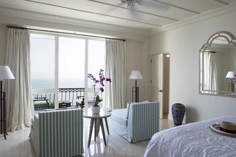 Une chambre lumineuse avec un coin salon et vue sur la mer.
