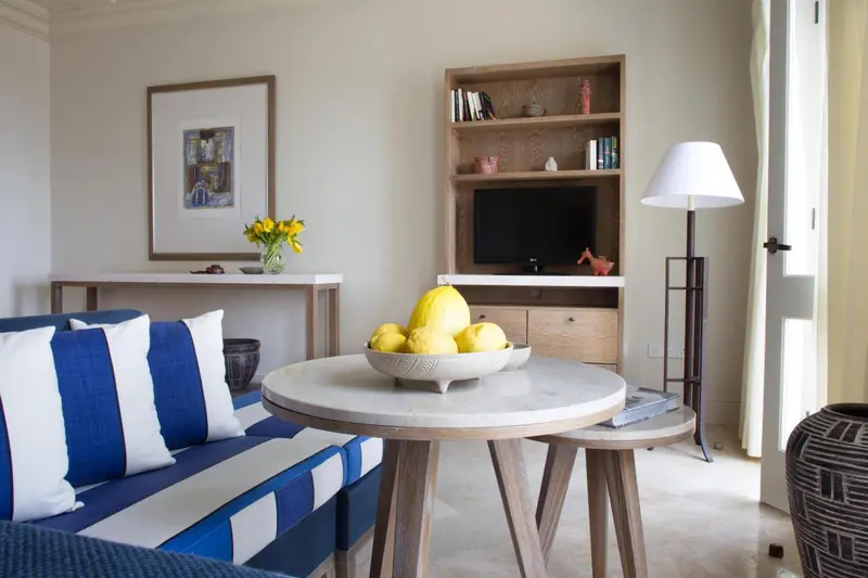 Un salon clair avec un canapé rayé, une table basse et une bibliothèque.