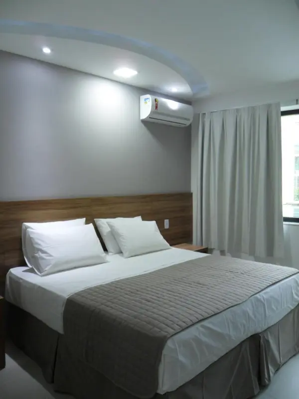 Une chambre lumineuse avec un grand lit recouvert d'une courtepointe.