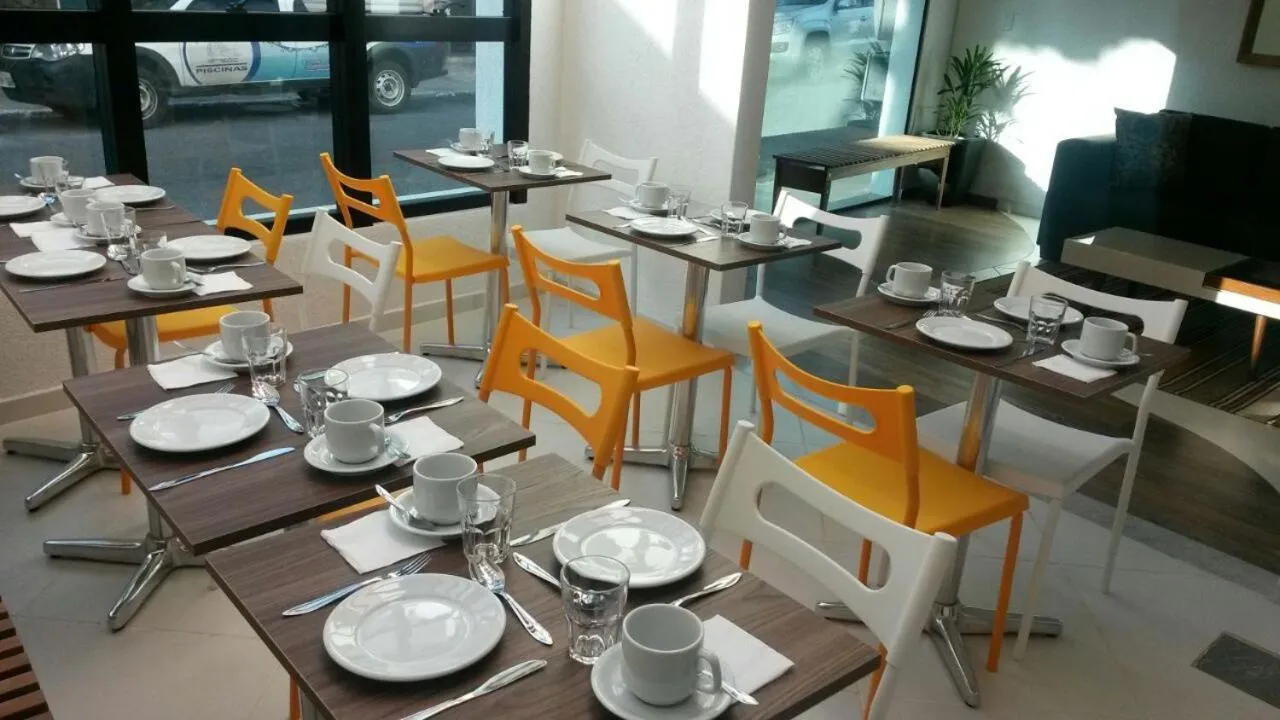 Une salle lumineuse avec des tables dressées pour le petit-déjeuner.