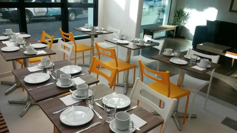 Une salle lumineuse avec des tables dressées pour le petit-déjeuner.