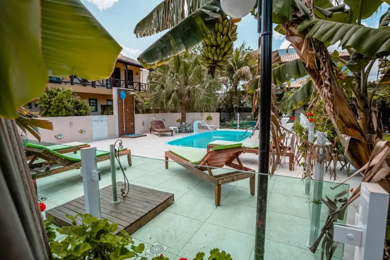 Transats et douches extérieures près d'une piscine ensoleillée.