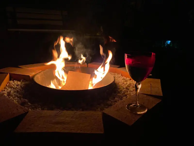 Un verre de vin rouge est posé près d'un feu de camp crépitant.