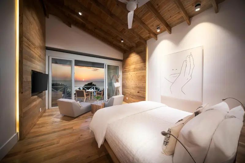 Une chambre lumineuse avec un grand lit et une vue sur la mer au coucher du soleil.