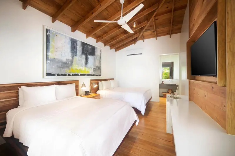 Chambre lumineuse avec deux lits simples et décoration murale.