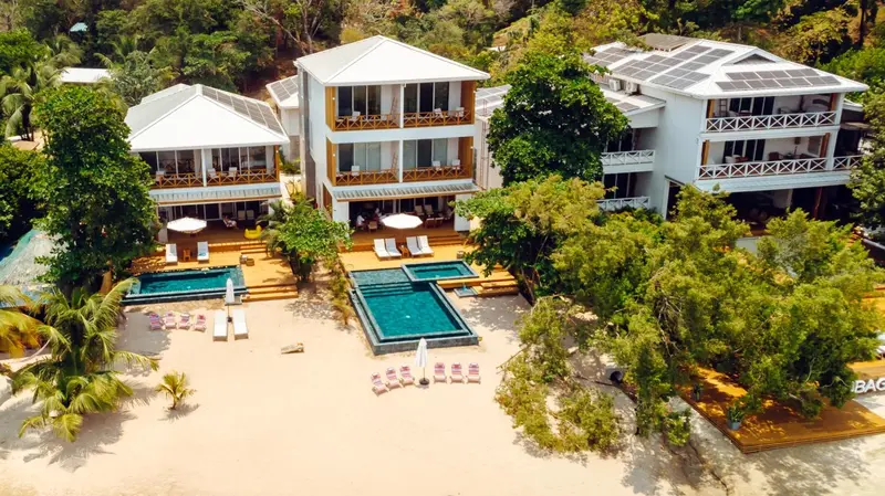 Vue aérienne d'un complexe hôtelier blanc avec piscine et plage.