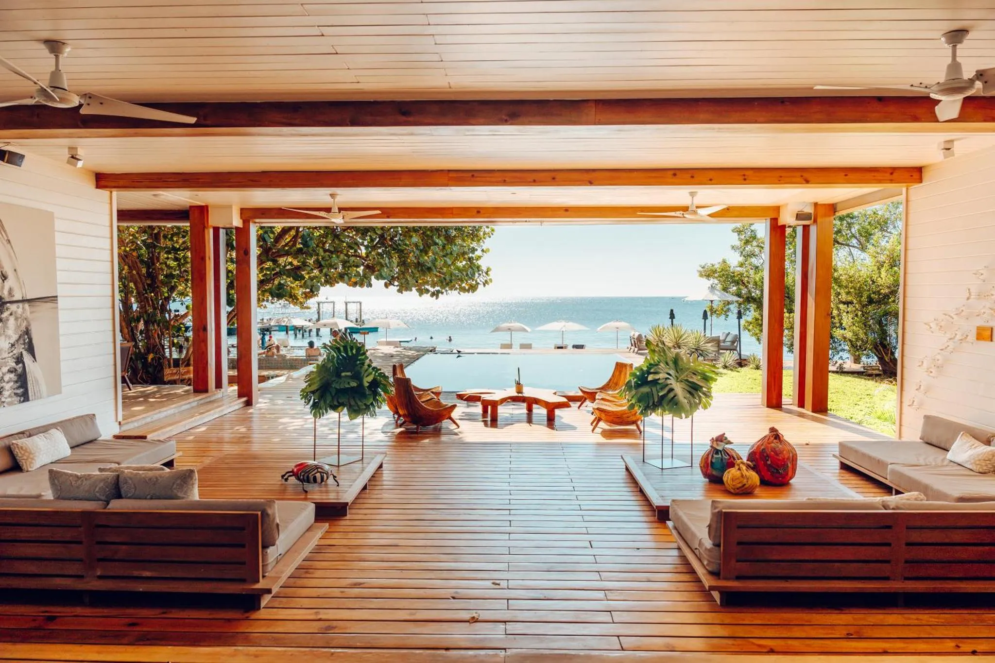 Espace de détente intérieur ouvert sur une terrasse et une piscine avec vue sur la mer.